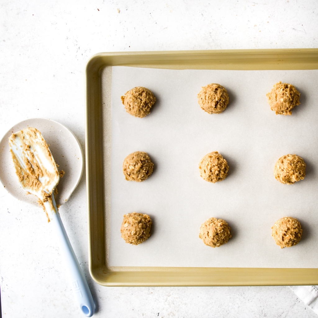 Cookie dough balls on a prepared cookie sheet.