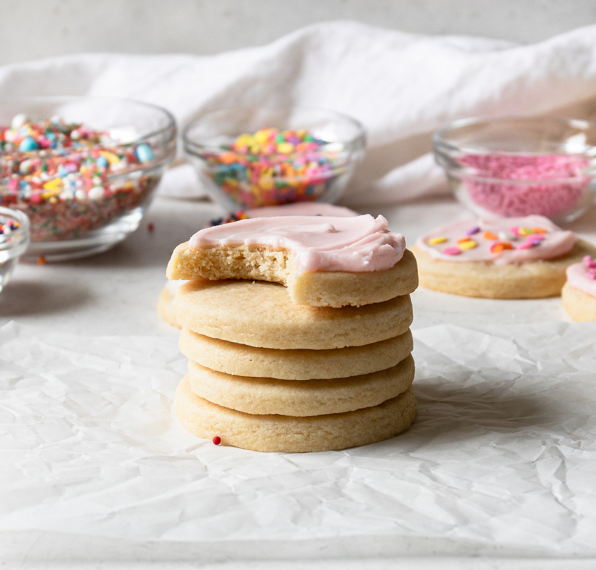 A stack of sugar cookies, one with pink frosting.
