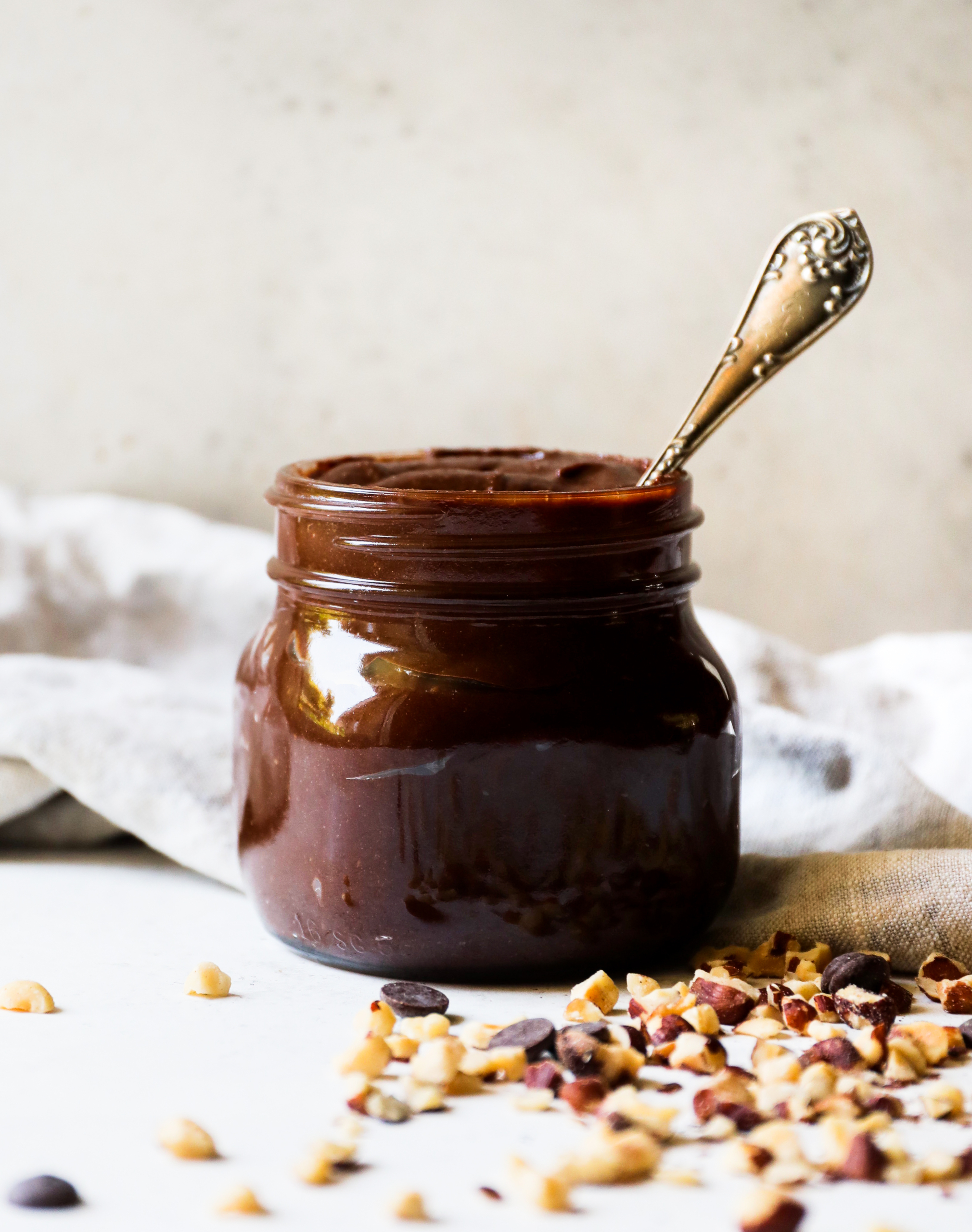 A glass jar filled with homemade nutella with a spoon sticking out of it.