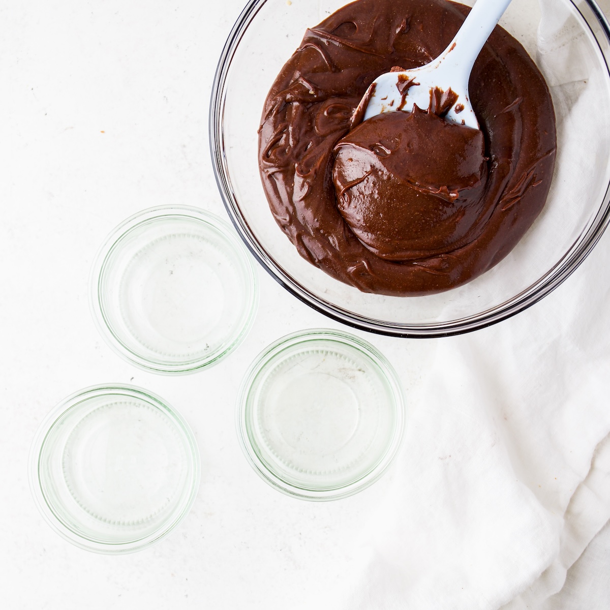glass bowl filled with Nutella and three empty glass containers.