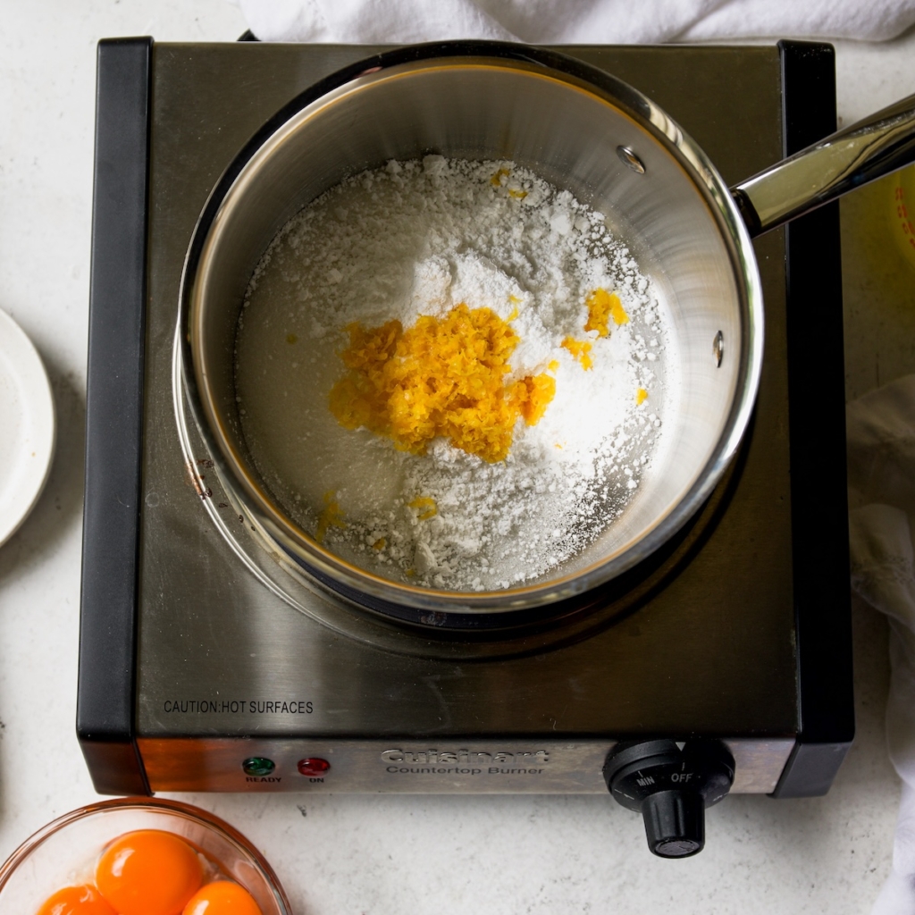 A saucepan with sugar and lemon zest.