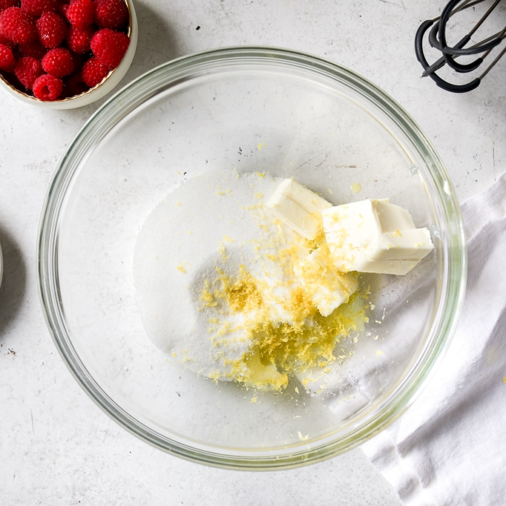 Butter, sugar, lemon zest, olive oil and almond extract in a glass bowl.