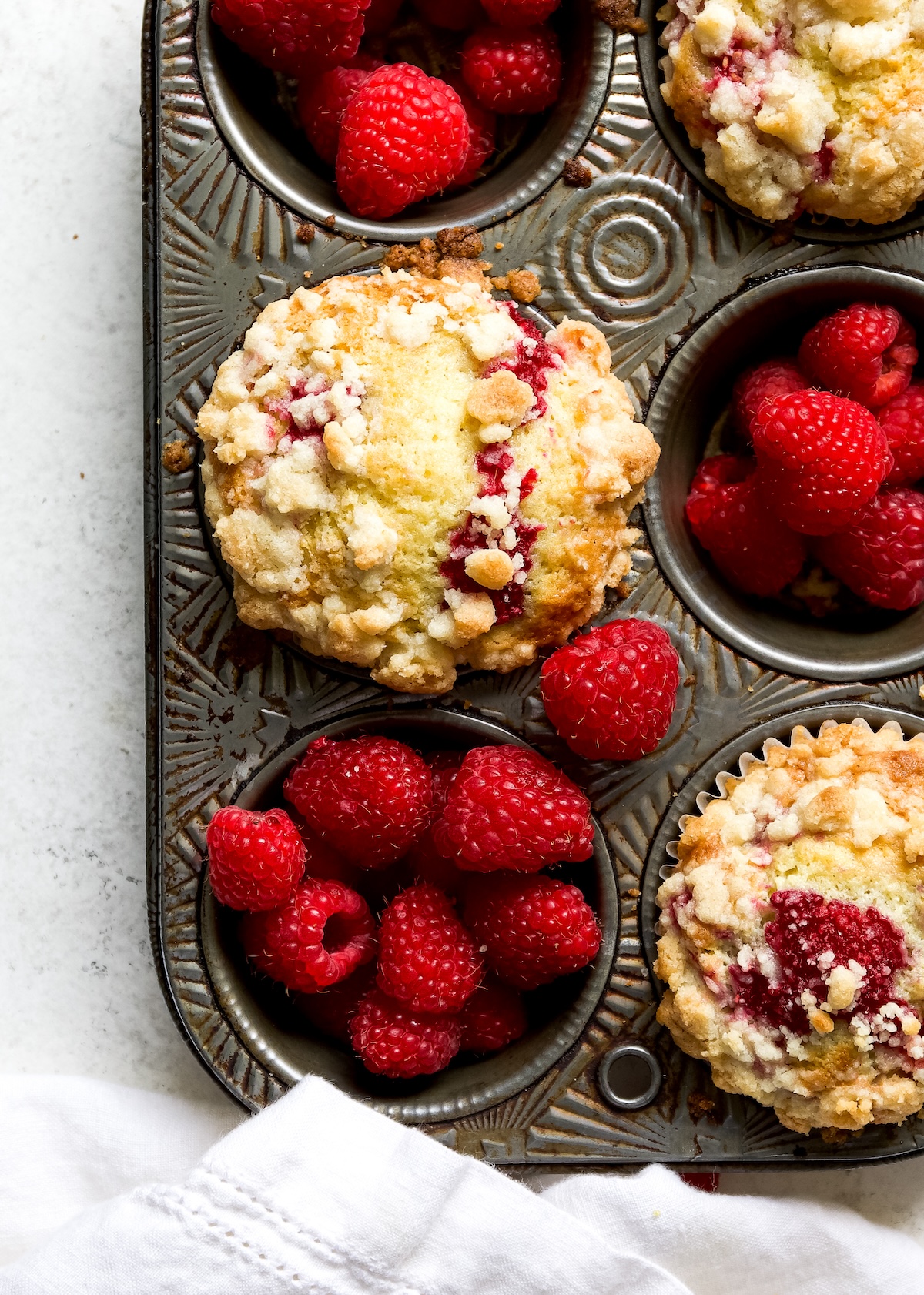 Half of a muffin tin with raspberry muffins in it.
