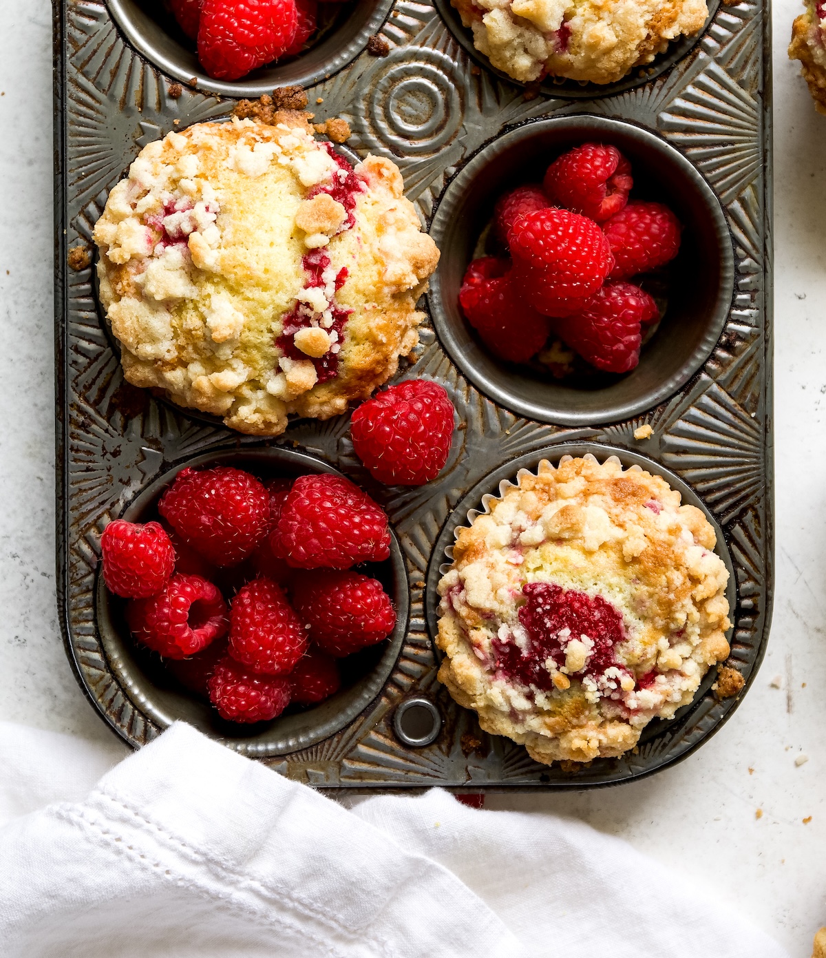 Raspberry Muffins in a muffin tin with fresh raspberries. 