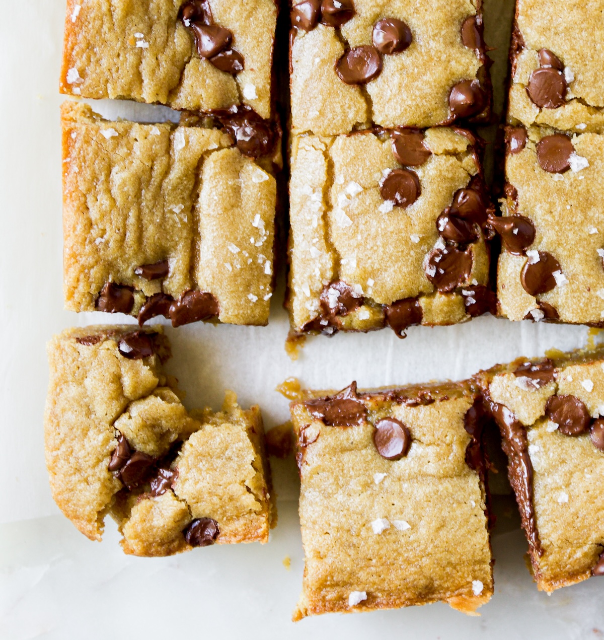 A bunch of blondie slices, on with a bite out of it.